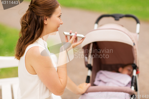 Image of happy mother with smartphone and stroller at park