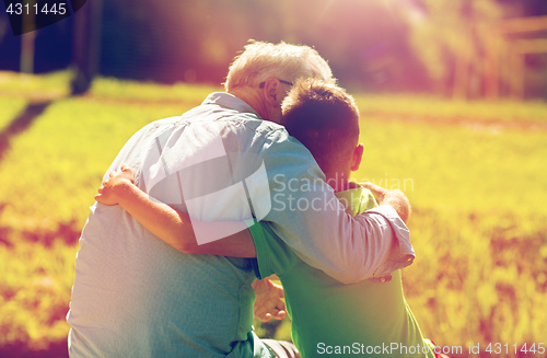 Image of grandfather and grandson hugging outdoors