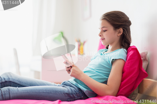 Image of smiling girl texting on smartphone at home