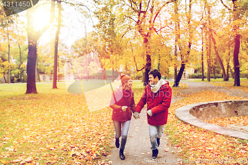 Image of happy young couple running in autumn park