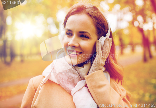 Image of woman in headphones listening music at autumn park