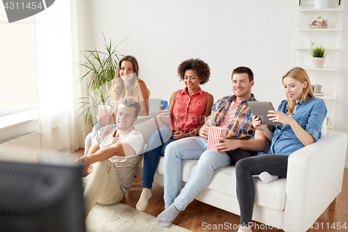 Image of friends with gadgets and beer watching tv at home