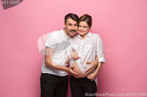 Image of Handsome man is listening to his beautiful pregnant wife\'s tummy and smiling