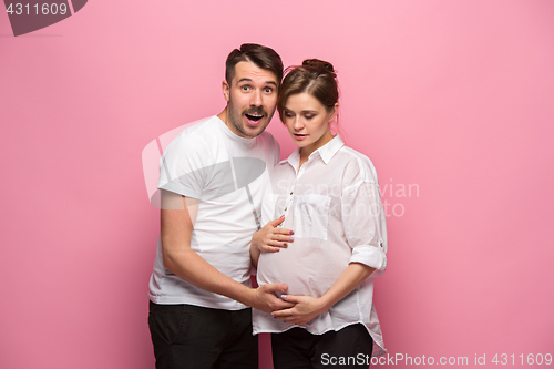 Image of Handsome man is listening to his beautiful pregnant wife\'s tummy and smiling