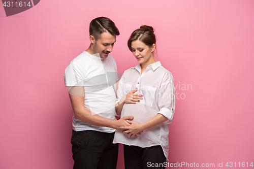 Image of Handsome man is listening to his beautiful pregnant wife\'s tummy and smiling