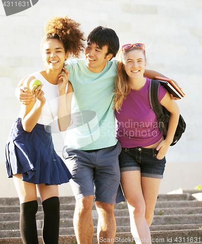 Image of cute group of teenages at the building of university with books huggings, back to school