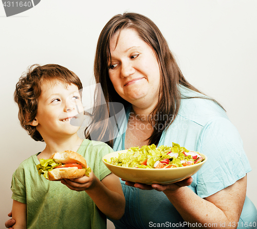 Image of fat woman holding salad and little cute boy with hamburger teasing