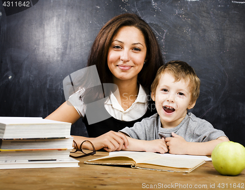 Image of little cute boy with teacher in classroom