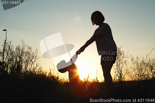 Image of Silhouette of a woman with her child at sunset.