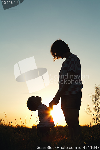 Image of Silhouette of a woman with her child at sunset.