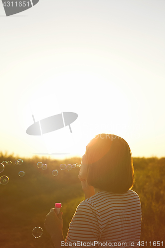 Image of Girl inflates soap bubbles.