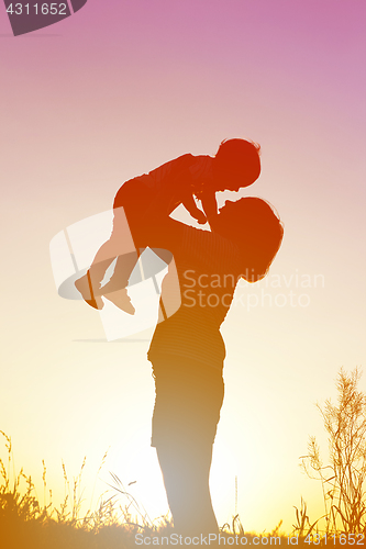 Image of Silhouette of a woman with her child at sunset.