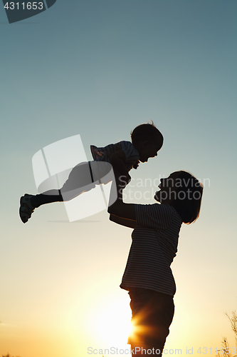 Image of Silhouette of a woman with her child at sunset.