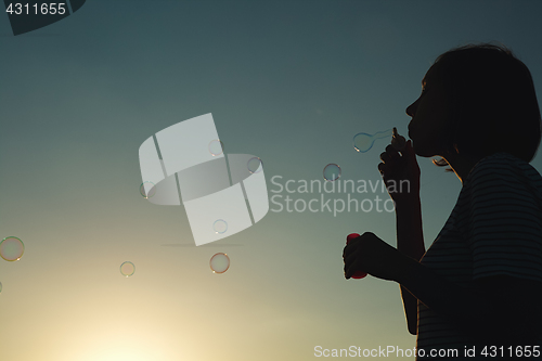 Image of Girl inflates soap bubbles.