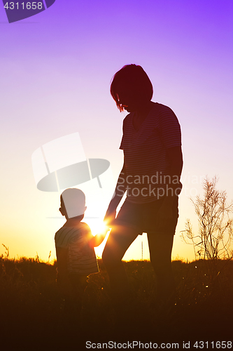 Image of Silhouette of a woman with her child at sunset.