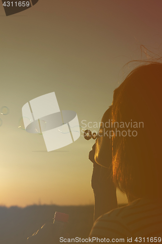 Image of Girl inflates soap bubbles.