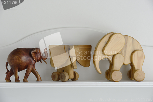 Image of three wooden elephant sculptures on a neutral background