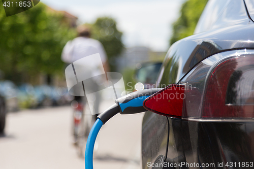 Image of Power supply plugged into an electric car being charged.