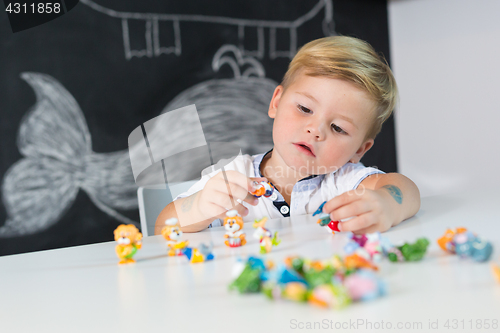 Image of Portrait of cute toddler boy playing with toys at the desk at home.