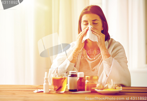 Image of sick woman with medicine blowing nose to wipe