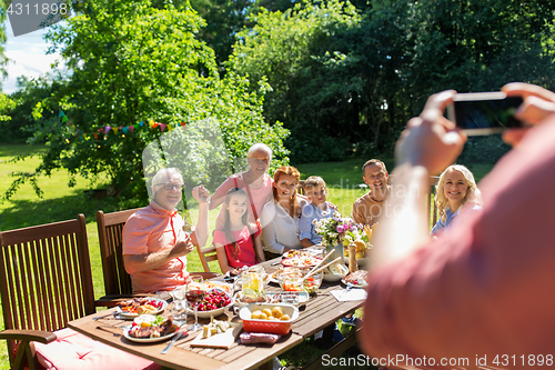 Image of happy family photographing by smartphone in summer