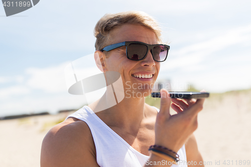 Image of smiling man calling on smartphone at summer beach