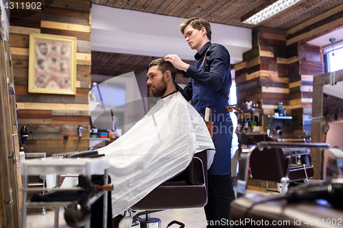 Image of man and barber styling hair at barbershop