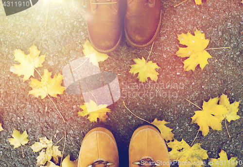 Image of couple of feet in boots and autumn leaves