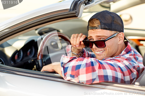 Image of happy young man in shades driving convertible car