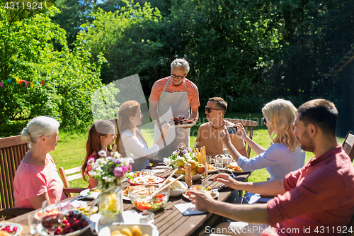 Image of happy family having dinner or summer garden party