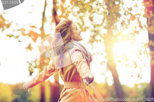 Image of beautiful happy young woman walking in autumn park