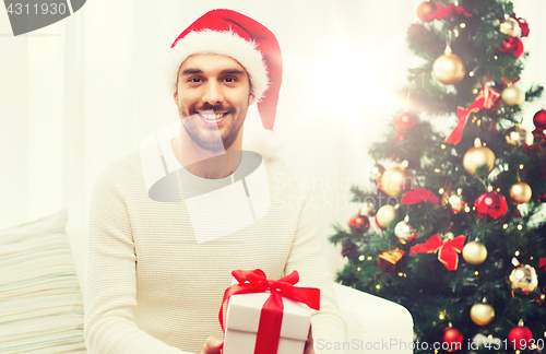 Image of happy man with christmas gift box at home