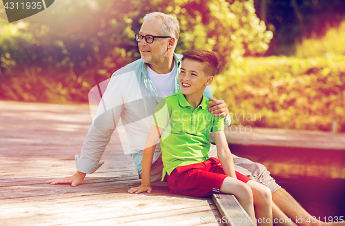 Image of grandfather and grandson sitting on river berth