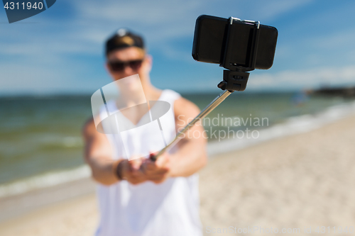 Image of man with smartphone taking selfie on summer beach