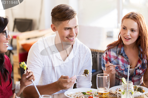 Image of happy friends eating and talking at restaurant