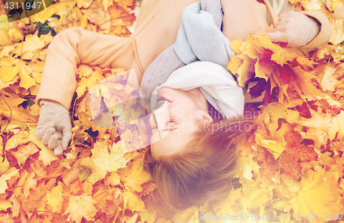 Image of beautiful happy woman lying on autumn leaves