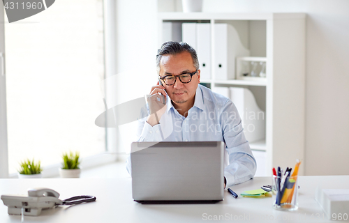 Image of businessman with laptop calling on smartphone