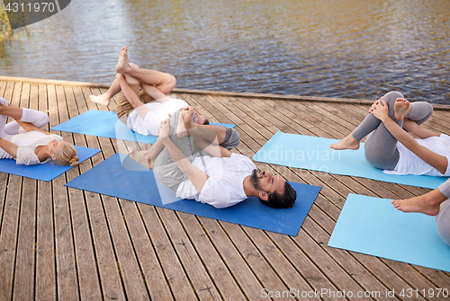 Image of group of people making yoga exercises outdoors