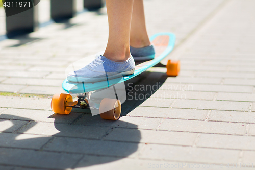 Image of female legs riding on longboard along road