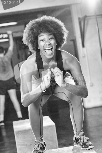 Image of black female athlete is performing box jumps at gym