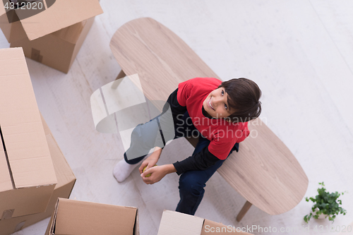 Image of boy sitting on the table with cardboard boxes around him top vie