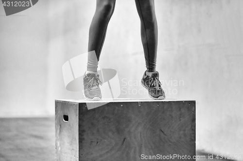 Image of black woman is performing box jumps at gym