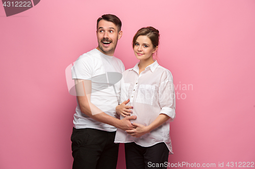 Image of Handsome man is listening to his beautiful pregnant wife\'s tummy and smiling