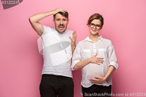 Image of The funny surprised handsome man and his beautiful pregnant wife\'s tummy