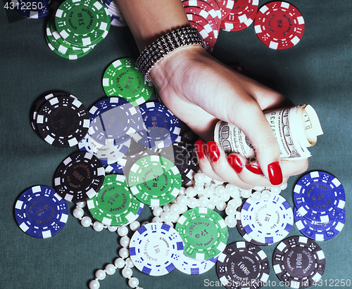 Image of hands of young caucasian woman with red manicure at casino table close up