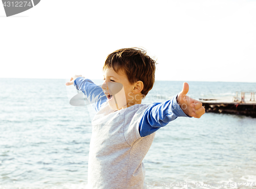 Image of little cute boy on sea coast thumbs up