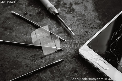 Image of Smartphone with a broken screen and repair tools.