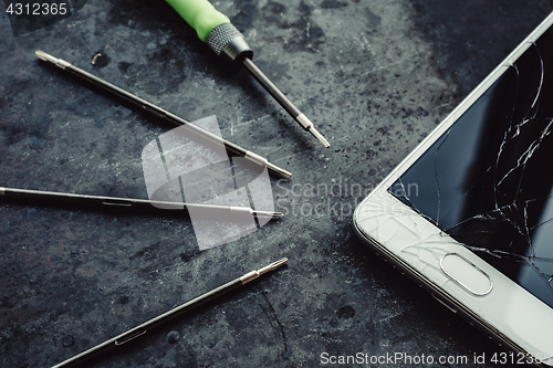 Image of Smartphone with a broken screen and repair tools.