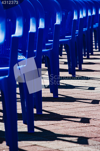 Image of Bright plastic chairs standing in a row.