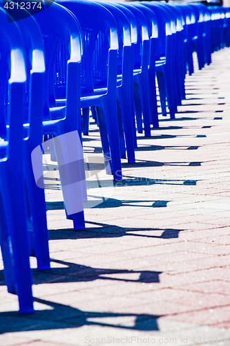 Image of Bright plastic chairs standing in a row.